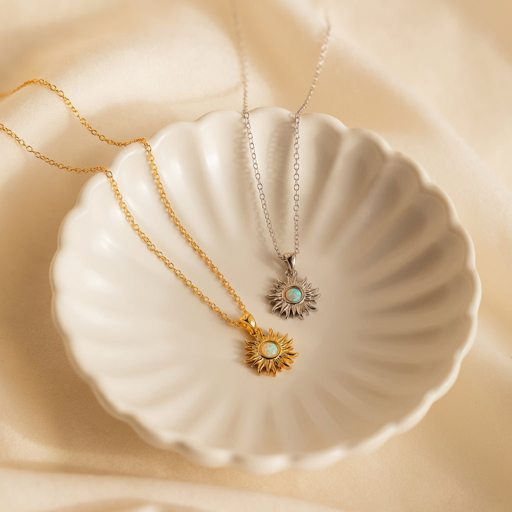 Two Opal Sun Necklaces, one gold and one silver, are displayed in a scalloped dish. This dainty necklace set is a thoughtful jewelry gift.