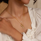 Woman wearing layered gold necklaces, including the Opal Sun Necklace with sun, moon, and star pendants over a white blouse—a dainty, thoughtful jewelry gift.