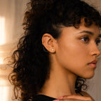 A woman with curly hair looks to the right, wearing gold Opal Kite Drop Earrings featuring a unique geometric design.