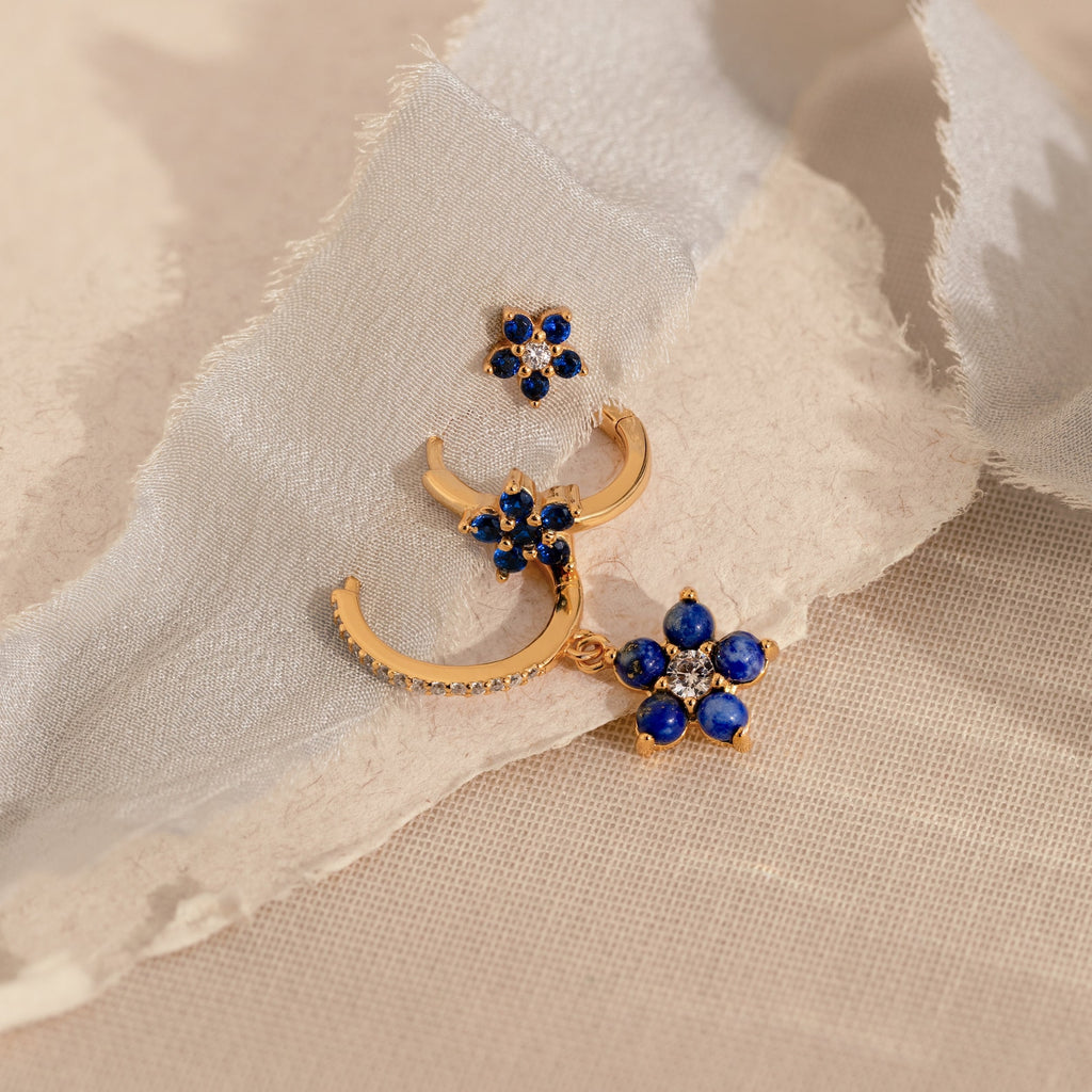 The Sapphire Flower Earrings Set features gold earrings with blue stones and diamonds, ideal for adding a touch of elegance to your jewelry collection.
