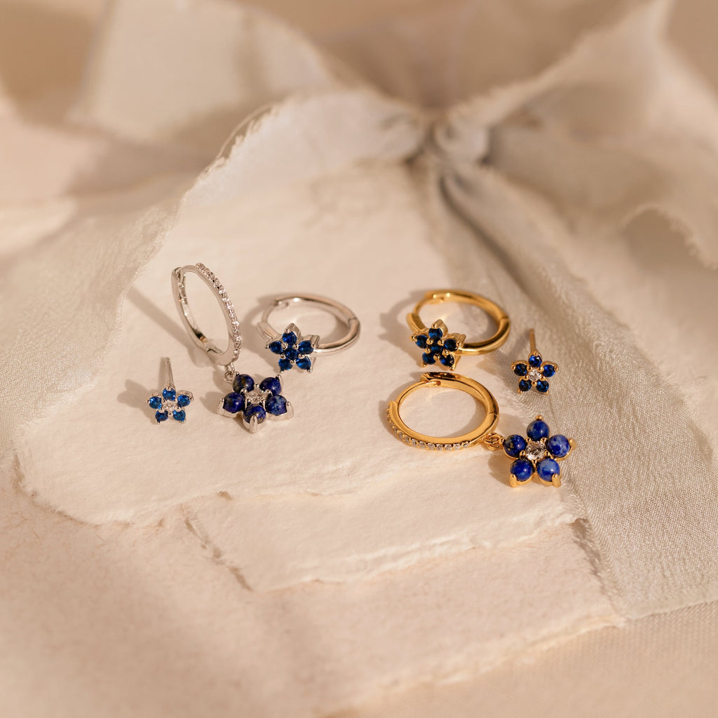 The Sapphire Flower Earrings Set in silver and gold is displayed on textured off-white paper.
