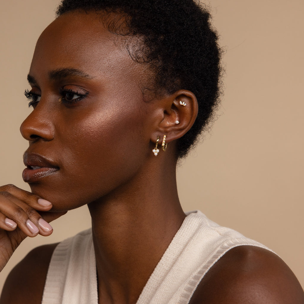 A woman with short hair wears Opal Link Hoops and a sleeveless cream top, gazing to the side.