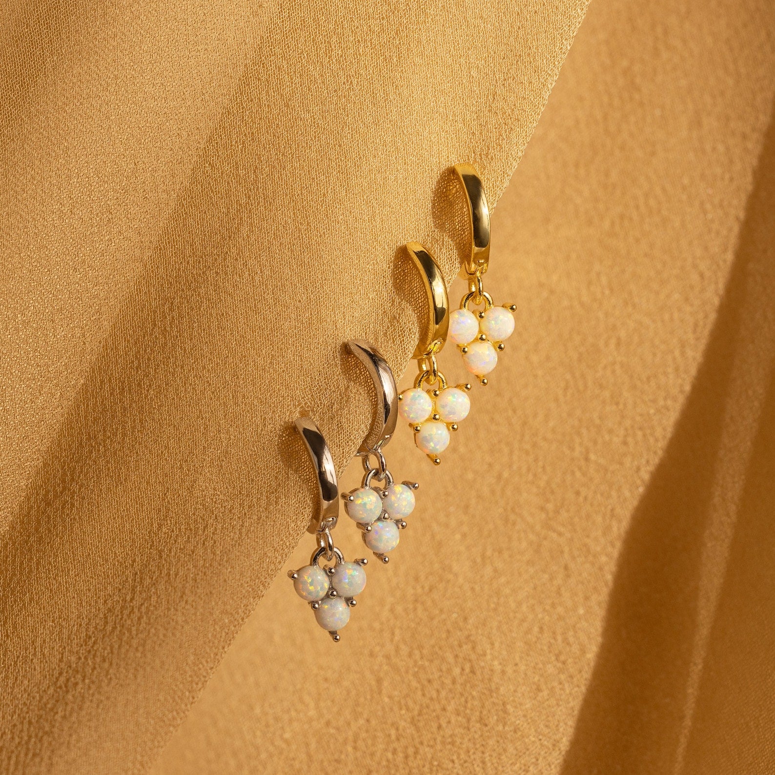 Two pairs of Opal Cluster Huggies in gold and silver, with clustered opal beads on a beige fabric background—perfect dainty hoop earrings for a unique bridesmaid gift.