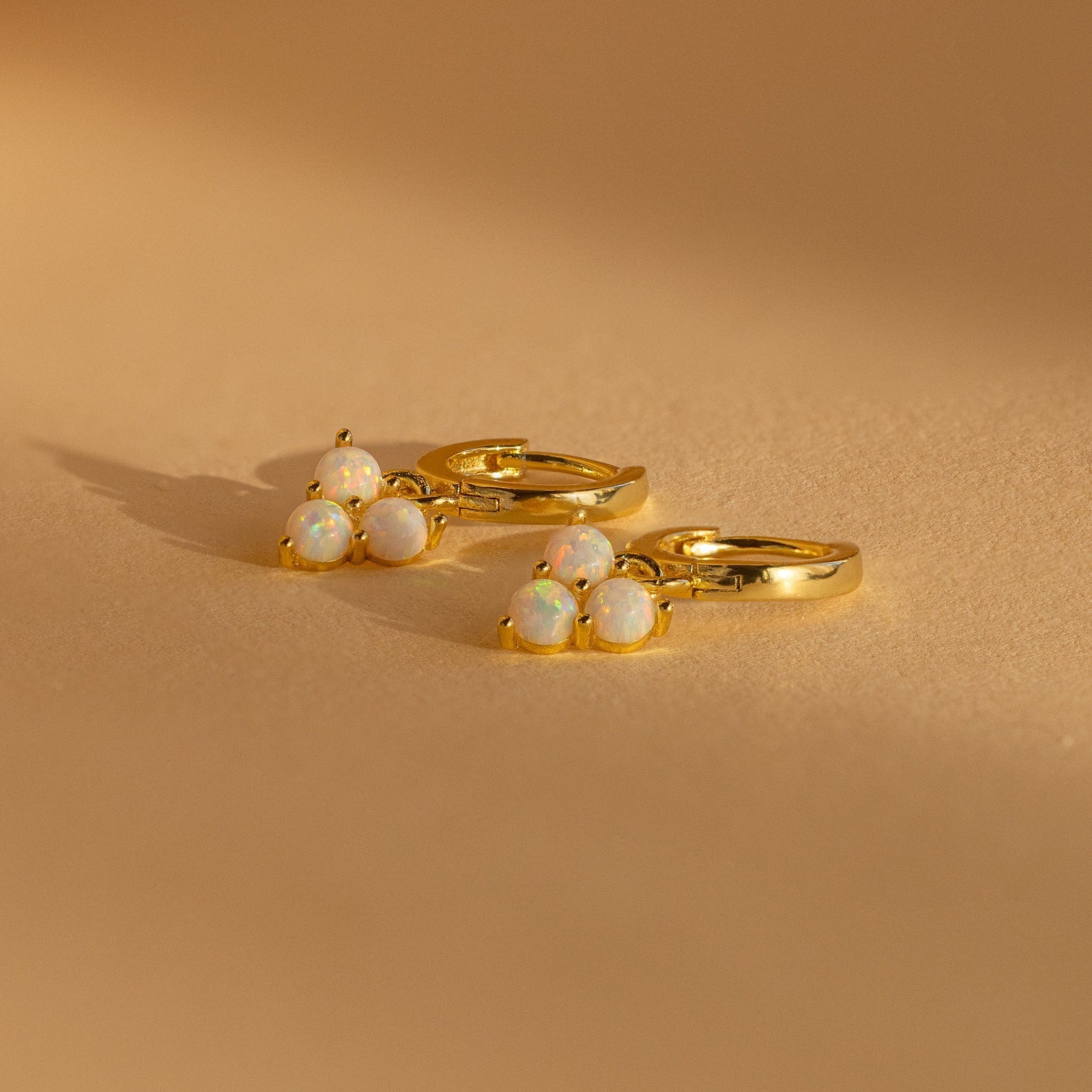 Opal Cluster Huggies featuring three small opal beads each, shown on a warm beige background—these dainty hoop earrings make a thoughtful bridesmaid gift.