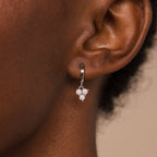 A close-up of an ear wearing Opal Cluster Huggies—dainty hoop earrings featuring small clustered white opals, perfect as a bridesmaid gift.