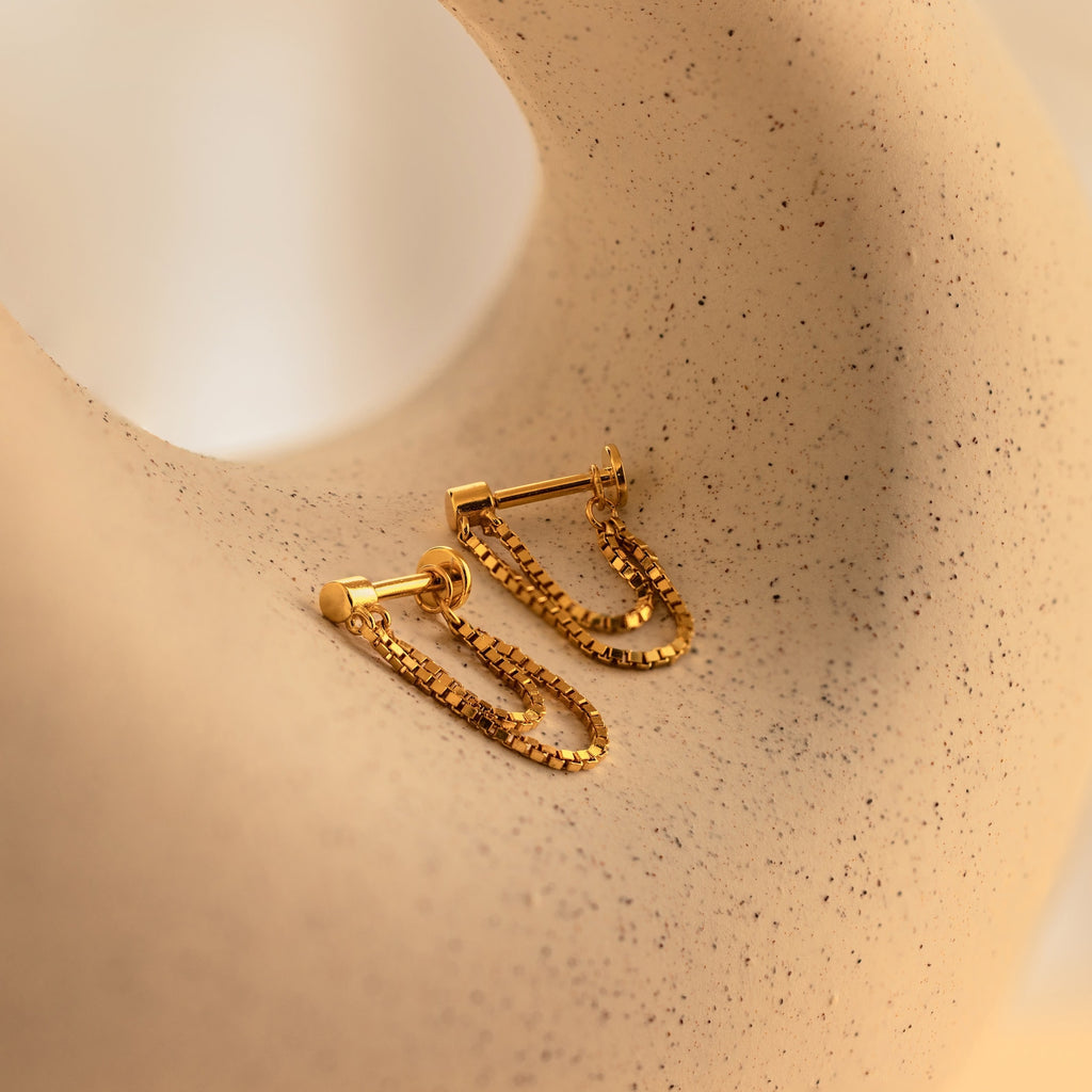 Flatback Chain Earrings showcased on a textured beige surface with black speckles—ideal minimalist gold chain earrings for stacking or wearing solo.
