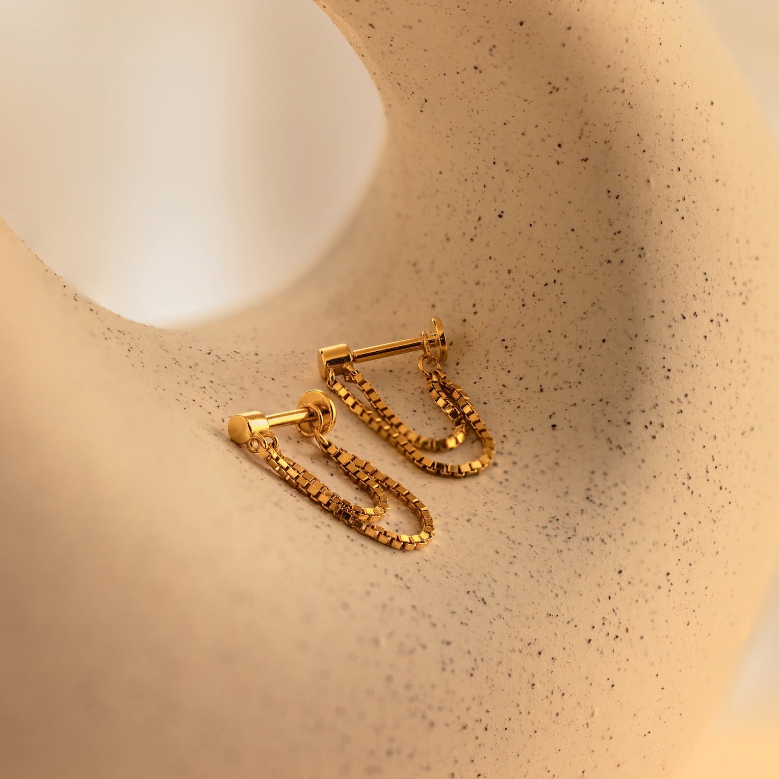 Flatback Chain Earrings showcased on a textured beige surface with black speckles—ideal minimalist gold chain earrings for stacking or wearing solo.