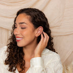A woman with curly hair wears the Opal Cluster Studs Set and has multiple cartilage piercings.