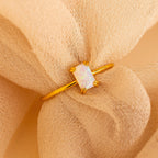 Opal Emerald Ring featuring a rectangular opal gemstone, elegantly presented on peach-colored fabric—an exquisite anniversary gift or unique engagement ring.