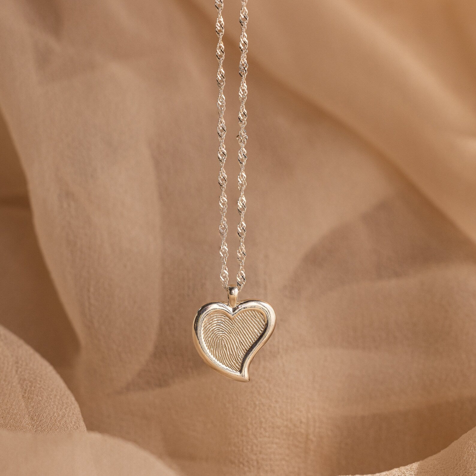 Fingerprint Heart Necklace featuring a unique fingerprint design, displayed on beige fabric—a perfect memorial gift or thoughtful gift for Mother's Day.