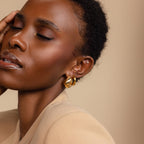 A woman with short hair and closed eyes poses gracefully, gently touching her face while wearing Bold Teardrop Studs.