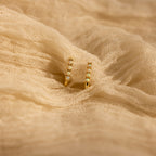 Opal Link Hoops: Gold hoop earrings featuring small white beads, inspired by elegant opal designs, shown on textured beige fabric.