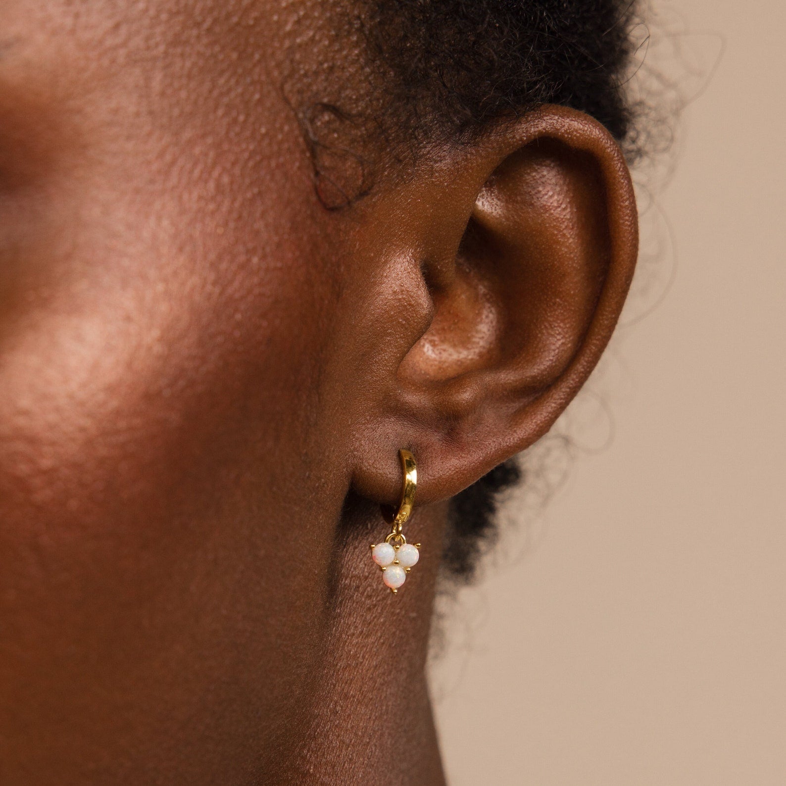 Close-up of Opal Cluster Huggies featuring delicate white opal beads on a person’s ear against a neutral background—perfect as a thoughtful bridesmaid gift.