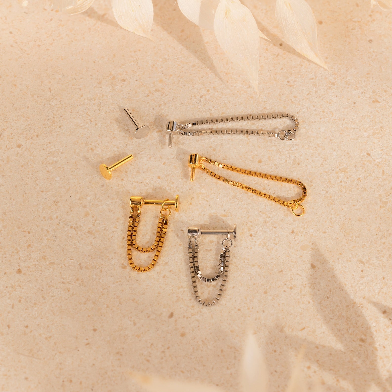 Flatback Chain Earrings in gold and silver are displayed on a beige textured surface, ideal for a minimalist look or creating your perfect ear stack.