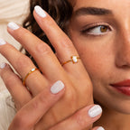 A woman with light nail polish wears the Opal Emerald Ring and a gold band, making it an elegant choice for an anniversary gift.