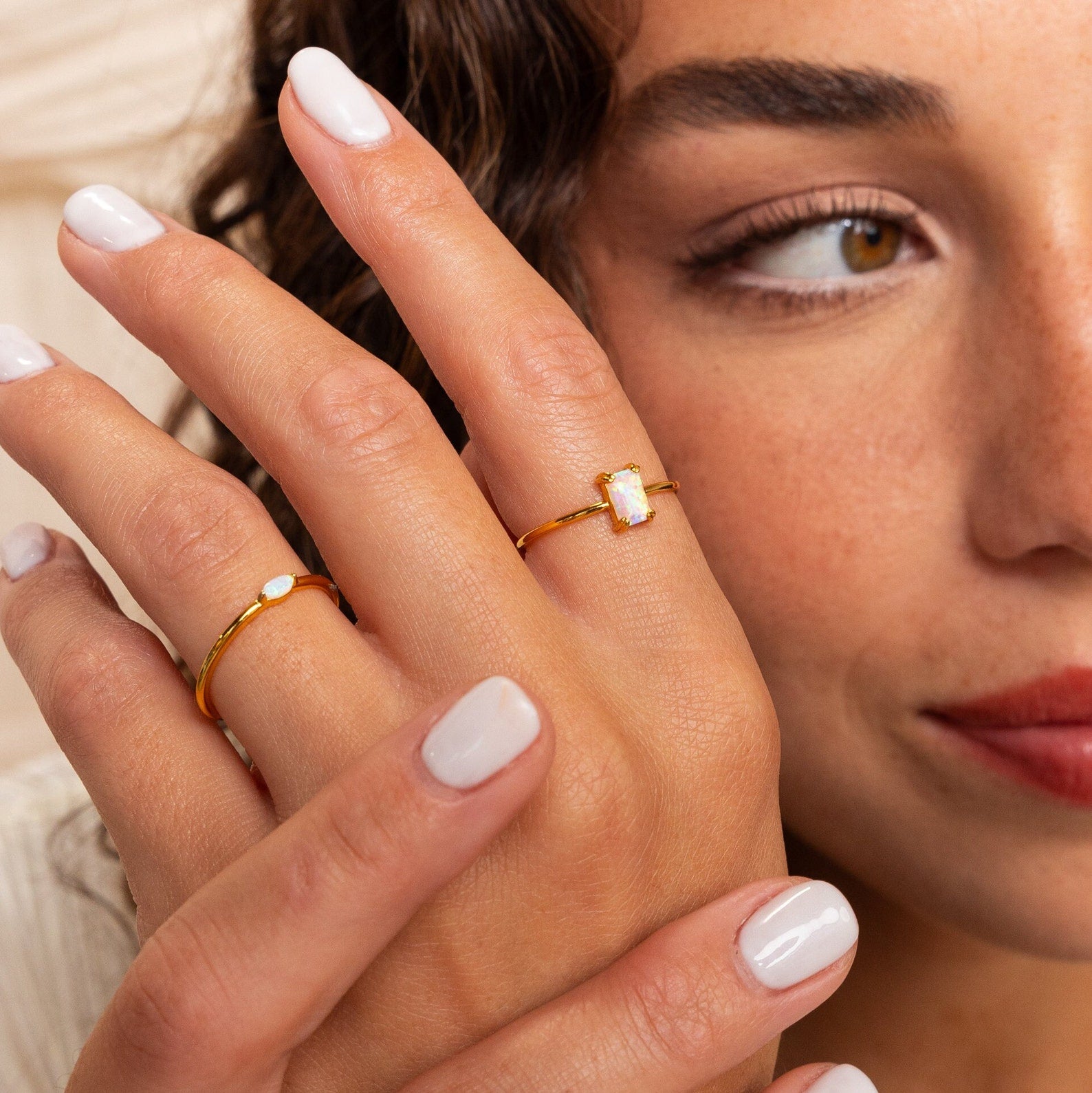 A woman with light nail polish wears the Opal Emerald Ring and a gold band, making it an elegant choice for an anniversary gift.
