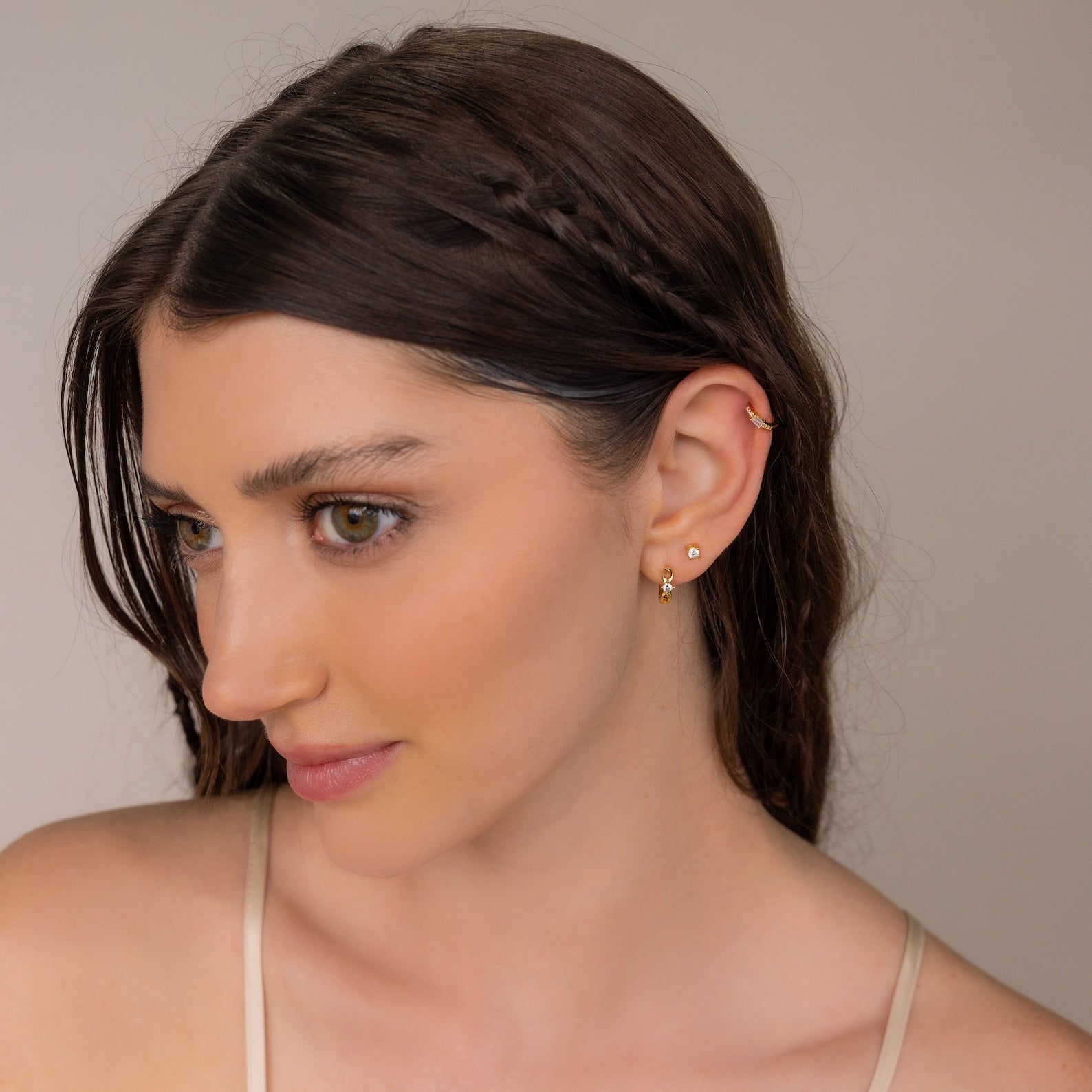Woman with braided brown hair wearing Diamond Infinity Hoops and a thin strap top, gazing to the side.