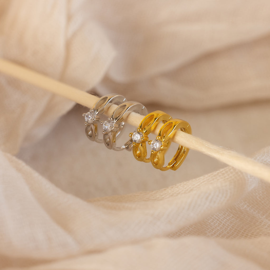 A close-up of the Diamond Infinity Hoops, paired with dainty earrings and romantic jewelry, captures timeless elegance.