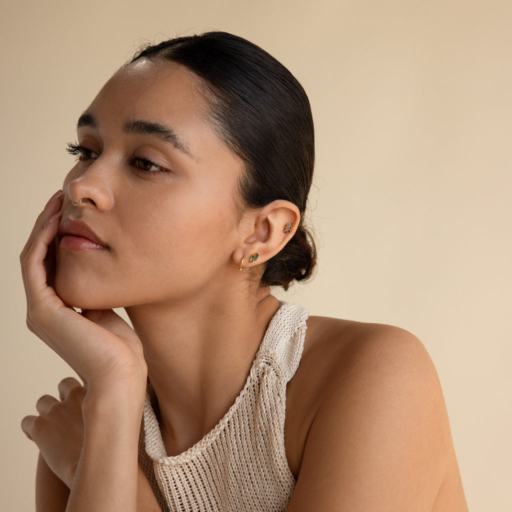 A woman with her hand on her face elegantly showcases the Agate Cartilage Earrings Set—a unique gift for best friends who love standout cartilage piercings.