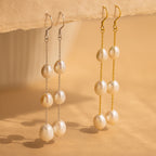 Close-up of two Long Pearl Dangle Earrings in Gold and Silver. 