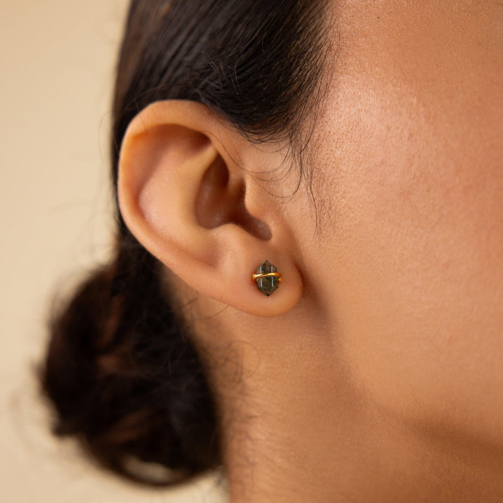 Close-up of a person’s ear wearing Herkimer Agate Studs—small, geometric green earrings ideal for fans of gemstone studs—shown against a neutral background.