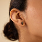 Close-up of a person’s ear wearing Herkimer Agate Studs—small, geometric green earrings ideal for fans of gemstone studs—shown against a neutral background.
