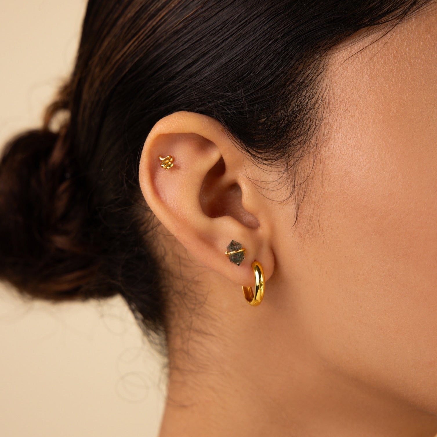 Close-up of a woman's ear with three earrings: a gold hoop, a small stud, and delicate Herkimer Agate Studs.