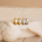 Two pairs of Mother of Pearl Inlay Huggies—one gold, one silver—are displayed on a neutral fabric background.