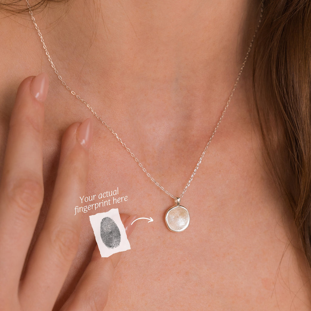 A woman wearing the Fingerprint Coin Necklace, a round silver pendant engraved with a unique fingerprint—an elegant and meaningful Mother’s Day gift.