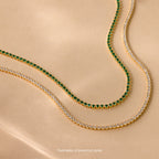 Two Mystery Necklaces—one with clear stones, one with vivid green—are displayed on beige, each elegant piece adding an air of intrigue and sophistication to any jewelry collection.