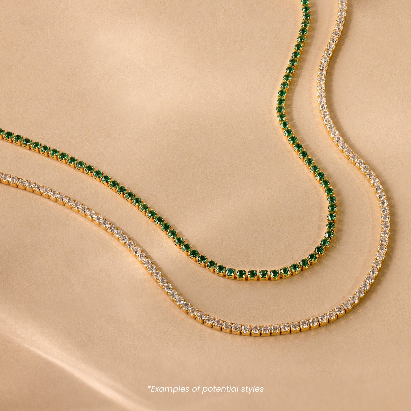 Two Mystery Necklaces—one with clear stones, one with vivid green—are displayed on beige, each elegant piece adding an air of intrigue and sophistication to any jewelry collection.