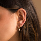 Close-up of model wearing Dainty Gold Pearl Huggies and Pearl Inlay Huggies. 