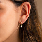Close-up of model wearing Dainty Pearl Huggies in Gold.