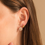 Close-up of a woman's ear wearing Daisy Huggies and a small gold hoop, highlighting her love for minimalist jewelry and flower-inspired earrings.