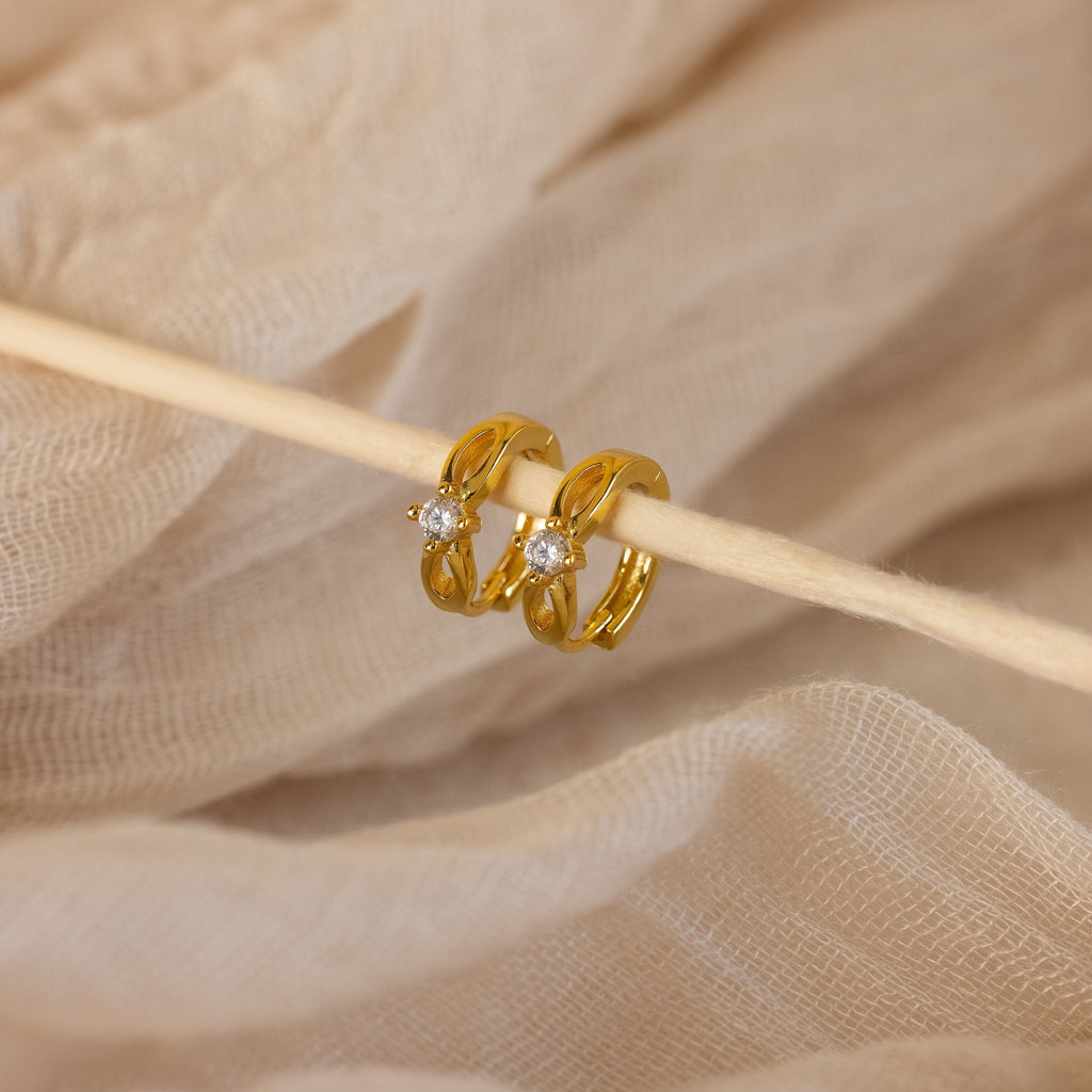 Diamond Infinity Hoops featuring small clear stones, ideal for romantic jewelry lovers, showcased on a beige fabric background.
