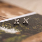 The Marquise Diamond Flower Studs rest on a book, highlighting their elegant floral design—ideal for weddings or any special occasion.