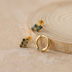 The Agate Cartilage Earrings Set features gold earrings with green stones, displayed elegantly on wood—an ideal gift for best friends and perfect for cartilage piercings.