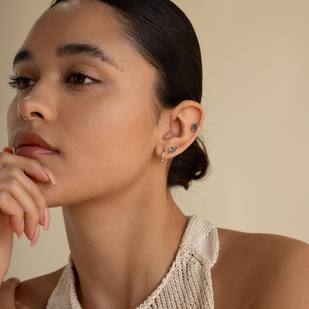 Woman with slicked back hair wearing small hoops and the Agate Cartilage Earrings Set, resting her chin on her hand and looking thoughtful—a stylish choice perfect for cartilage piercings and a unique gift for best friends.