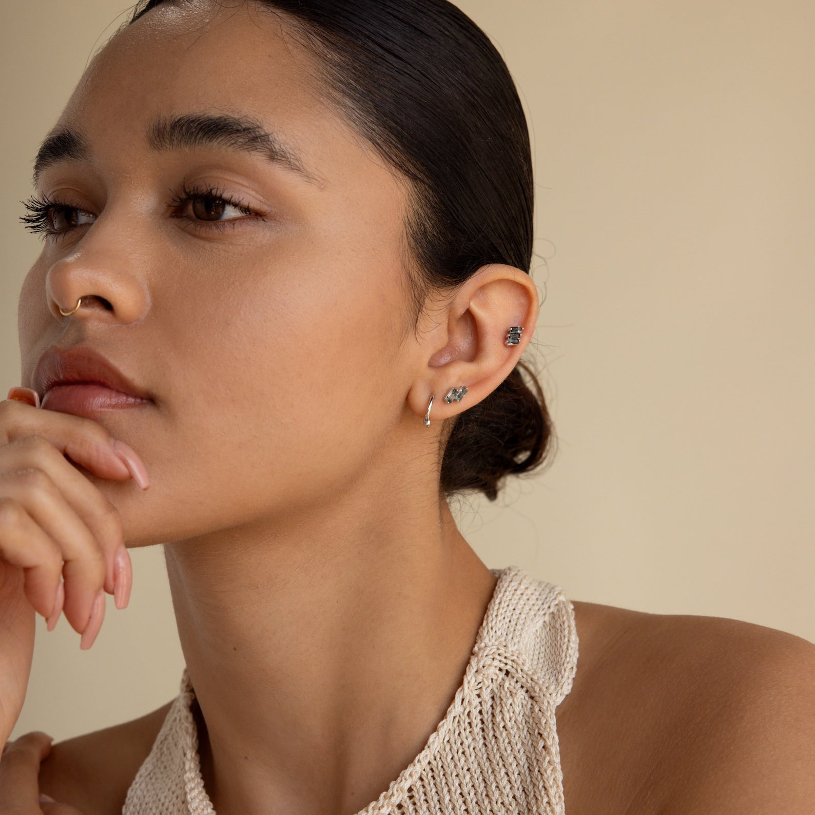 Woman with slicked back hair wearing small hoops and the Agate Cartilage Earrings Set, resting her chin on her hand and looking thoughtful—a stylish choice perfect for cartilage piercings and a unique gift for best friends.