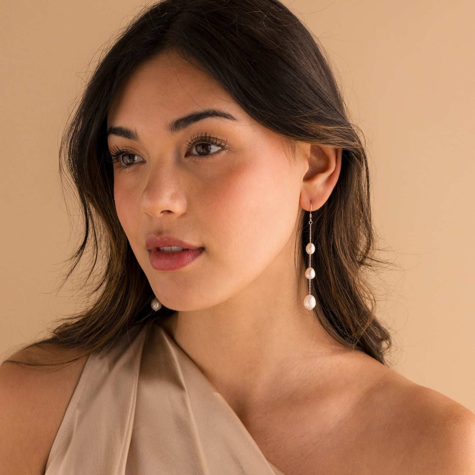 Model wearing long silver pearl chain earrings.
