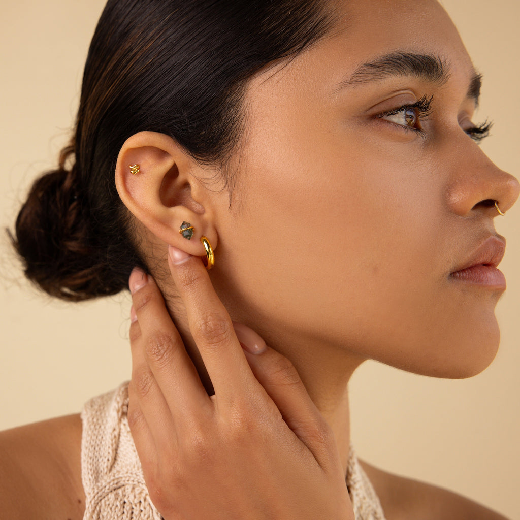 Woman with smooth skin and pierced ear wears Herkimer Agate Studs, touching her ear gently with her hair styled in a low bun.