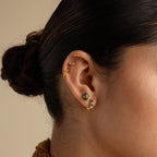 A close-up of a woman's ear with her hair in a bun, featuring the Herkimer Malachite Studs in gold and green malachite.