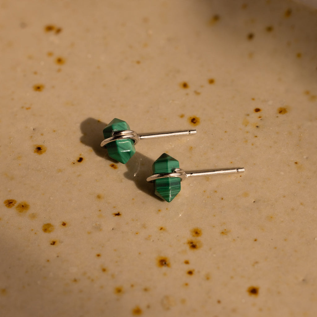 Two green Herkimer Malachite Studs with silver posts sit on a beige, speckled surface, highlighting their modern geometric gemstone earring style.