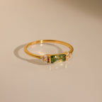 The Agate Baguette Ring showcases a rectangular green gemstone with sparkling diamonds on each side, all set in gold and photographed on a neutral background.