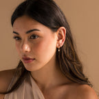 A woman with long hair in a dress wearing elegant Mother of Pearl Inlay Huggies.