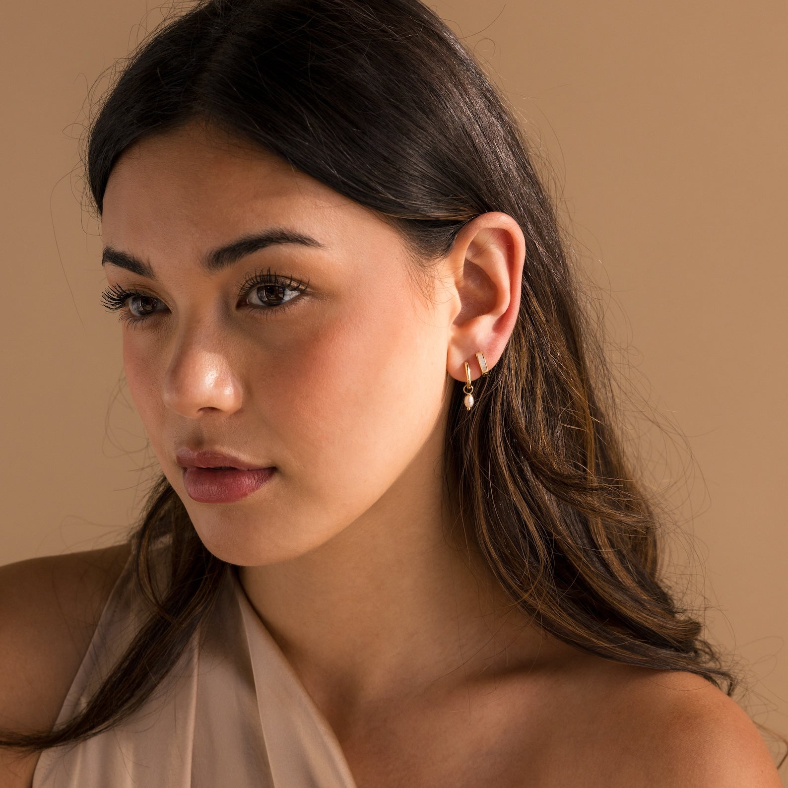 A woman with long hair in a dress wearing elegant Mother of Pearl Inlay Huggies.