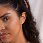 Woman with long dark hair and pink ribbon wears Trio Cluster Pearl Studs, looking toward the camera.