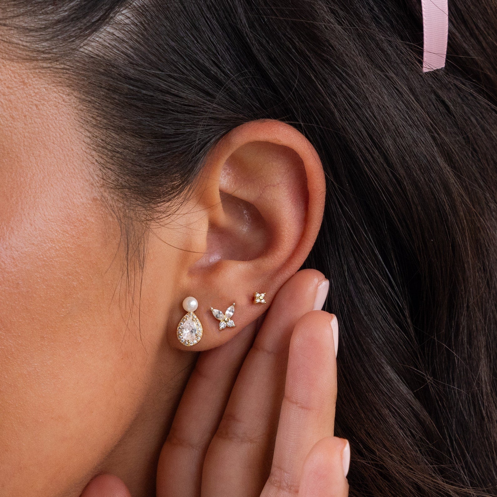 Close-up of a woman's ear adorned with Pearl Diamond Teardrop Studs, as her hand gently touches her ear.