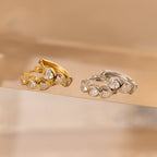 Two rings with heart-shaped stones—one gold, one silver—are displayed on a clear surface, pairing perfectly with the Diamond Bezel Heart Huggies.