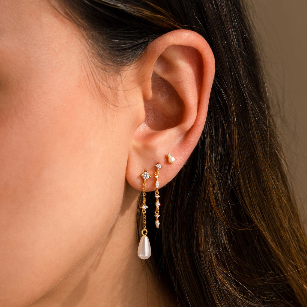Close-up of a woman's ear wearing Diamond Pearl Chain Earrings, featuring a pearl teardrop charm and elegant diamond studs.